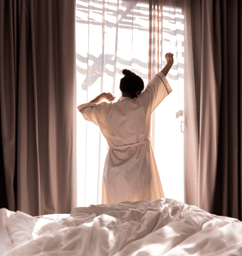 Person stretching by window in bedroom